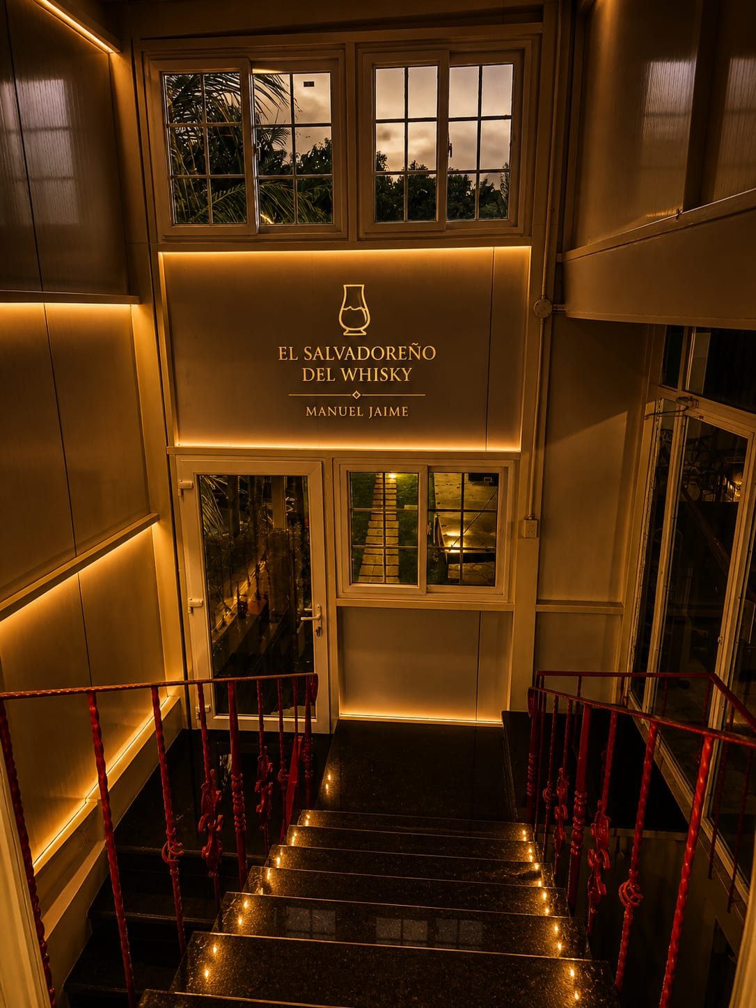 Entrada de la cava con escaleras iluminadas y letrero dorado El Salvadoreño del Whisky · Manuel Jaime